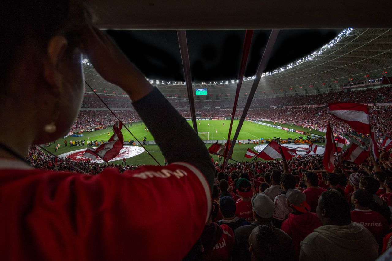 gallery-6 Lively soccer match at packed Brazilian stadium with cheering fans and vibrant atmosphere.